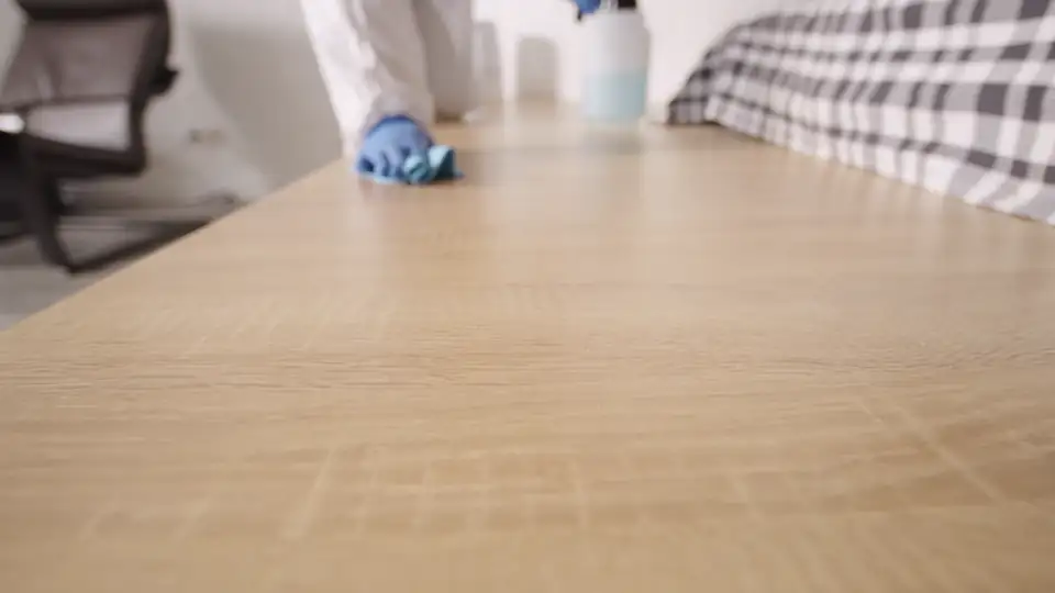 A gloved hand wiping down a surface with a cleaning cloth